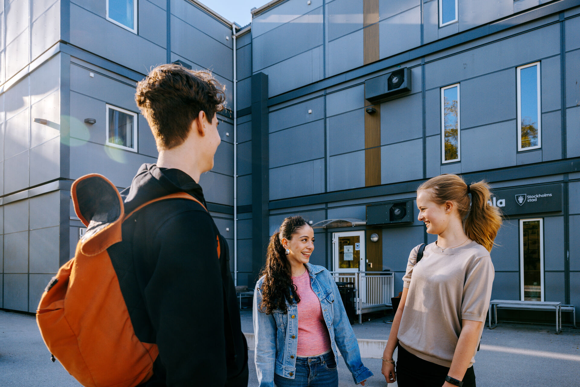 Elever samtalar på skolgården utanför Expandias modullösning på Ekens skola i Hammarby Sjöstad, med modulbyggnader i bakgrunden.