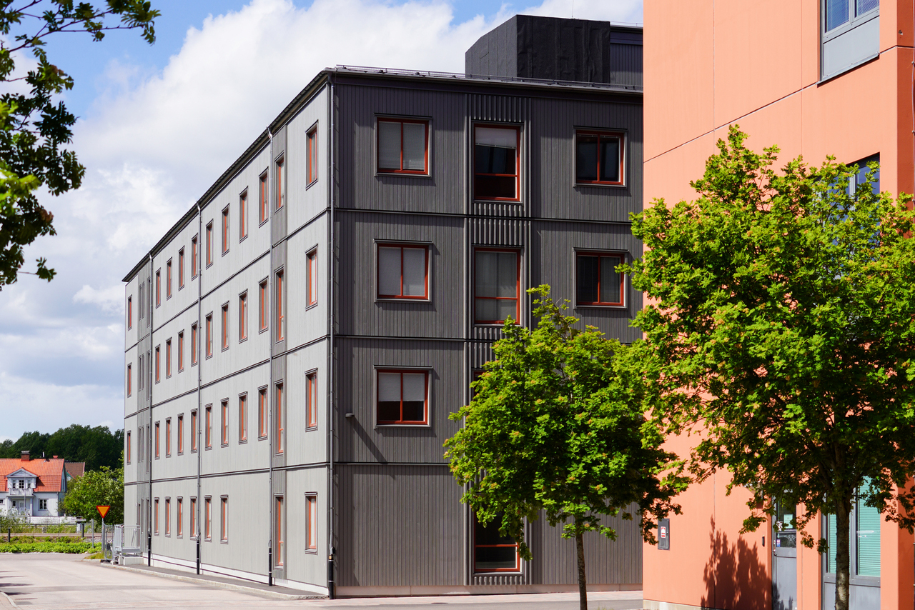 Exteriör vy av kontorsmoduler från Expandia vid Centralsjukhuset i Karlstad. Den flervånings grå modulbyggnaden med stora fönster är placerad intill sjukhusets ordinarie byggnader och omgiven av grönska, vilket visar hur Expandias kontorsmoduler smidigt integreras i sjukhusmiljön för att skapa moderna och flexibla arbetsytor.