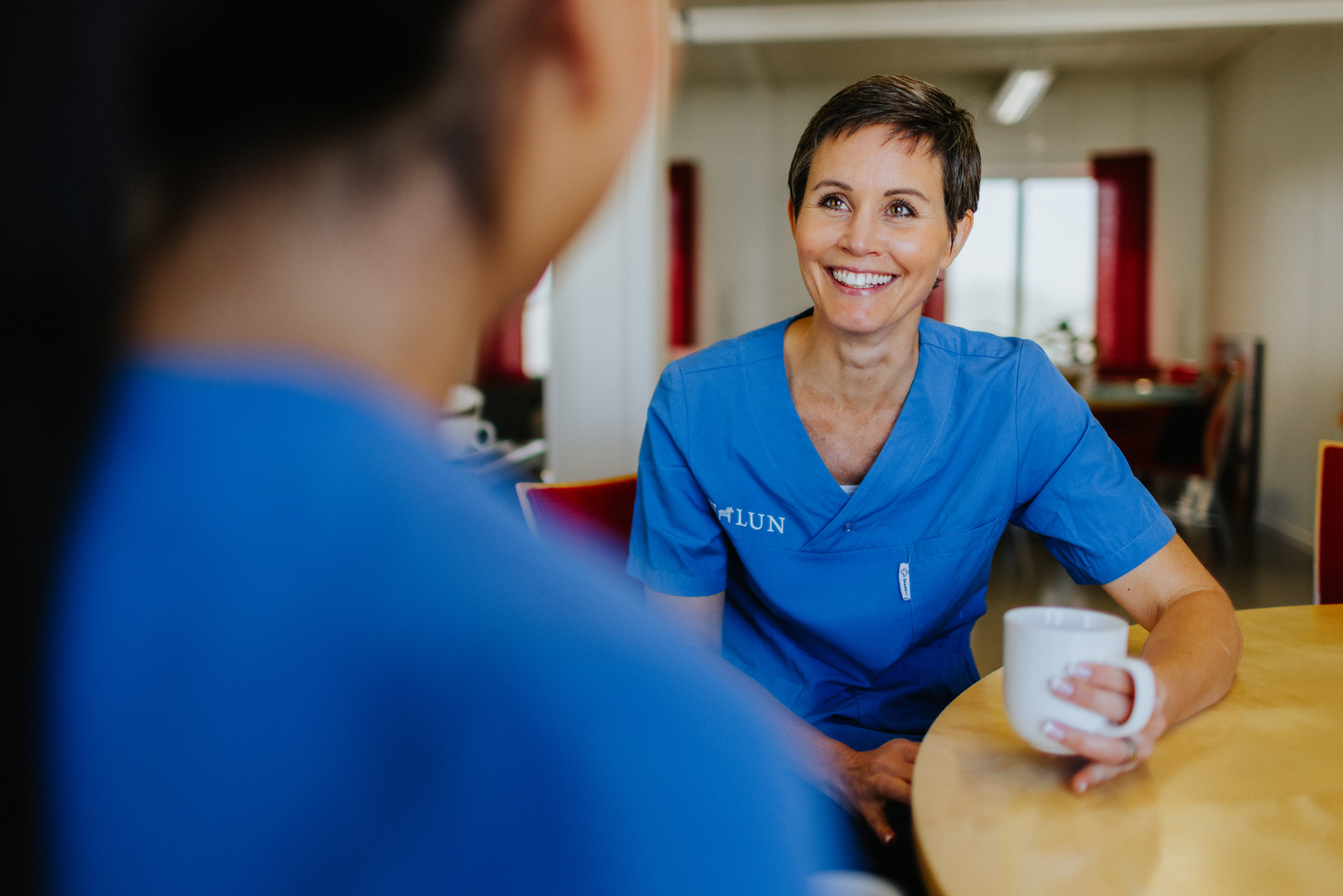 Vårdpersonal ler med kaffekopp i handen