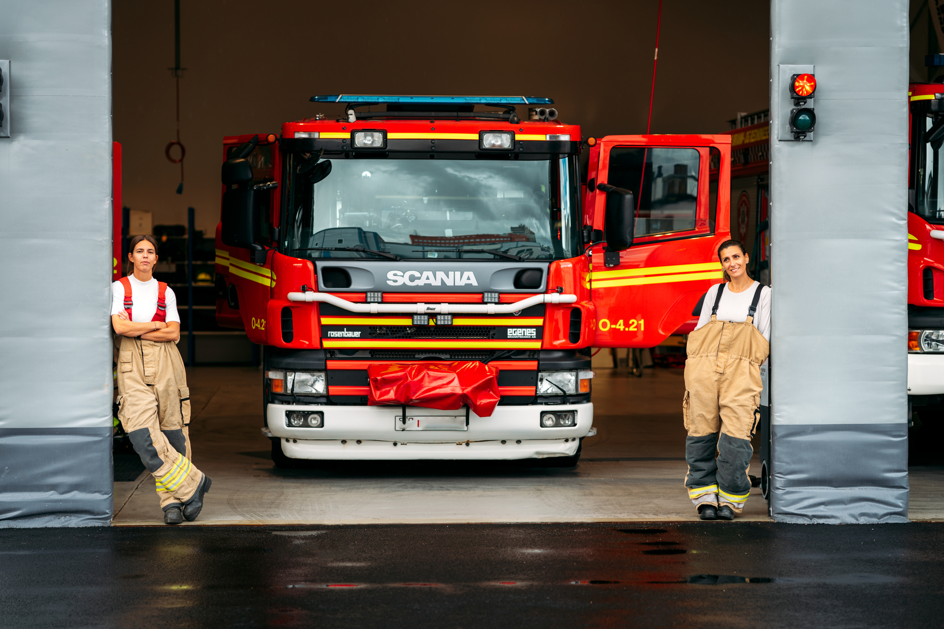 två brandmän framför en byggnad med brandbil